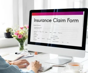 person at computer monitor filling out insurance claim form