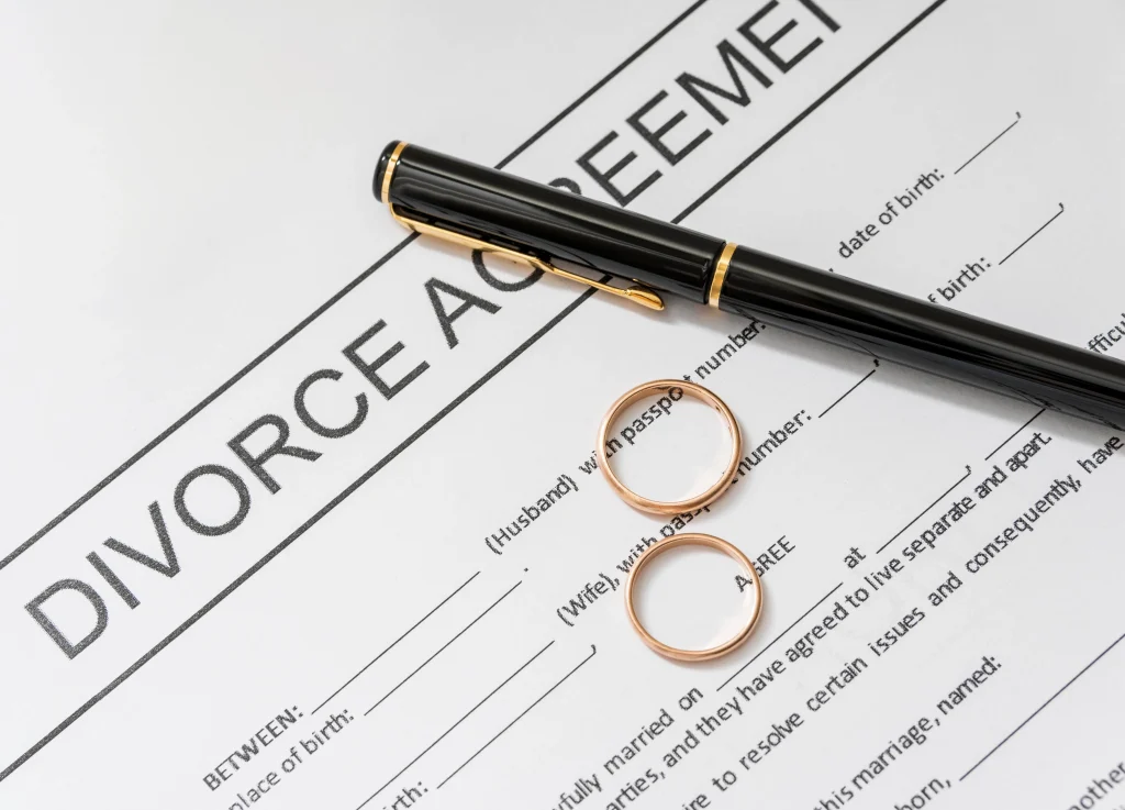 close up of divorce agreement paperwork with gold rings on top