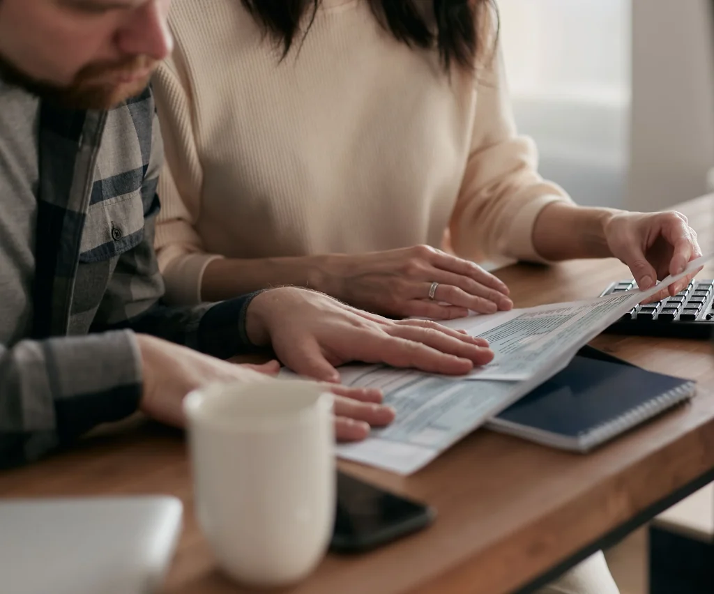 couple reviewing insurance forms together at home desk with coffee mug