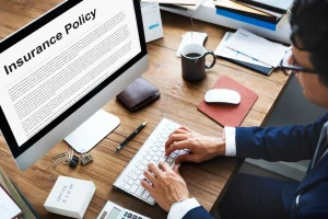 man typing at desk in Colorado with insurance policy document on computer monitor