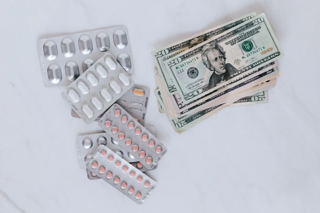 prescription pill blister packs next to stack of 20 dollar bills
