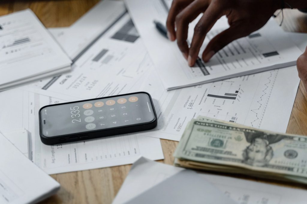 Financial documents, cash and a smartphone calculator used to estimate monthly health insurance expenses