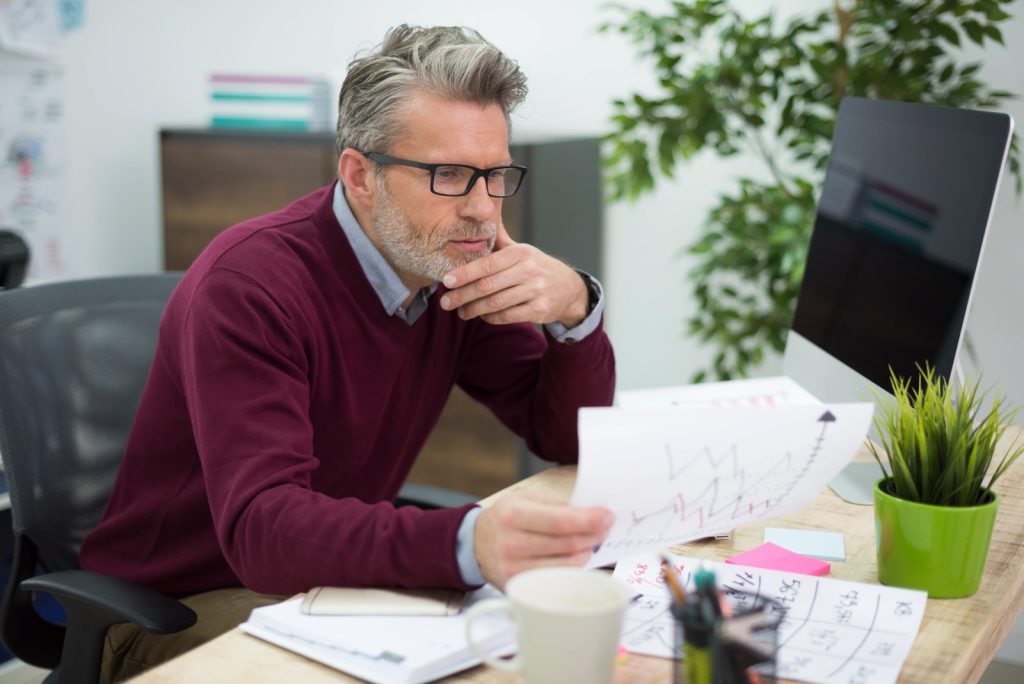 Businessman analyzing financial reports and charts to evaluate insurance costs and employee benefits