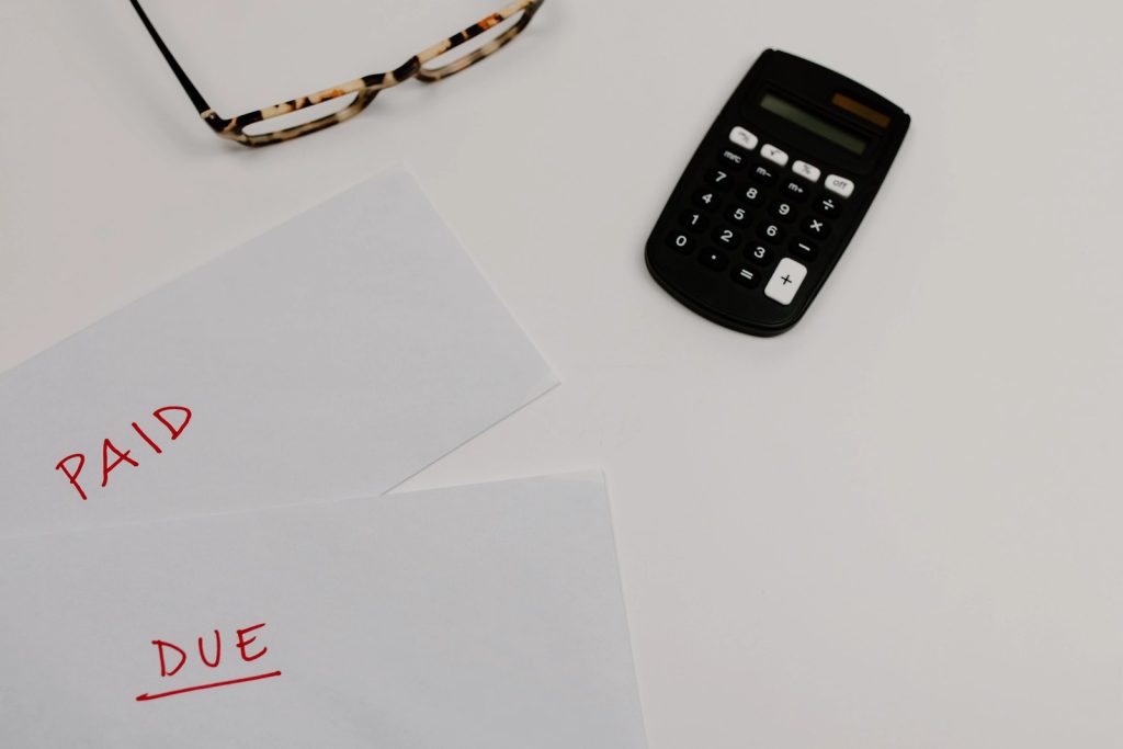 Paid and unpaid bills beside a calculator representing employee vision insurance costs and expenses