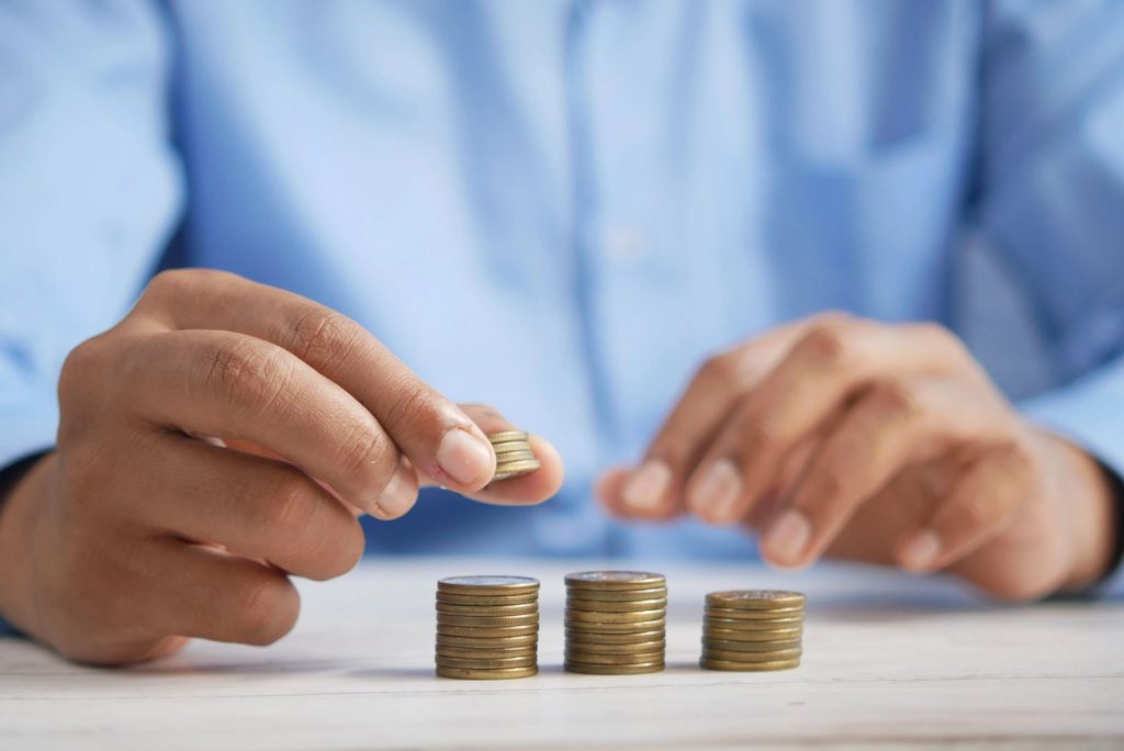 Person stacking coins to represent savings and budgeting for health insurance premiums in 2026